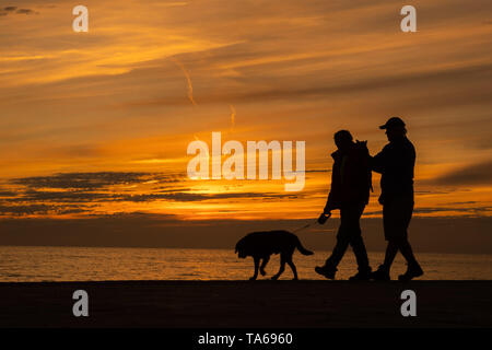 Aberystwyth Wales UK, Mittwoch, 22. Mai 2019 Deutschland Wetter: Silhouette Menschen gehen mit ihrem Hund entlang der Strandpromenade bei Sonnenuntergang in Aberystwyth an einem milden kann Abends, am Ende eines Tages der warmen Frühlingssonne an der Westküste von Wales. Photo Credit: Keith Morris/Alamy leben Nachrichten Stockfoto