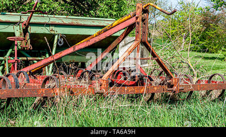 Alte, rostige und verlassenen landwirtschaftlichen Maschinen unter dem Gestrüpp auf einem Obsthof, kongskilde Anbauer triland, sonniger Frühlingstag in Oensel Süden Lim Stockfoto