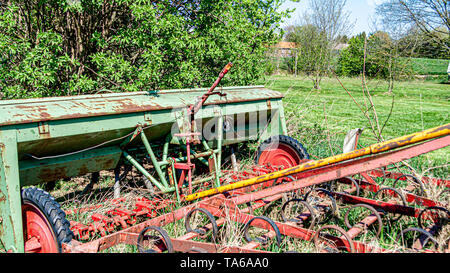 Alte, verrostete und verlassenen landwirtschaftlichen Maschinen auf einem Obsthof, kongskilde triland Anbauer, sonniger Frühlingstag in der Landschaft in Oensel Süd-limburg in Stockfoto