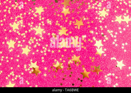 Golden Star Konfetti auf Rosa fuchsia Hintergrund. Festliche Kulisse mit leuchtenden Sternen. Stockfoto