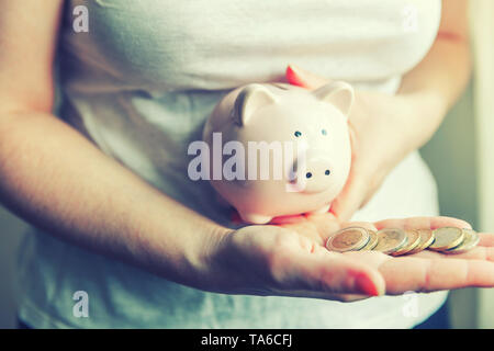 Weiblich frau Hände halten rosa Sparschwein und Euro Münzen. Speichern Investitionsbudget business Reichtum Rente Finanzen Geld Banken- Konzept Stockfoto