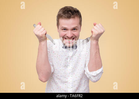 Hungrige Mann mit Messer und Gabel zu essen Stockfoto