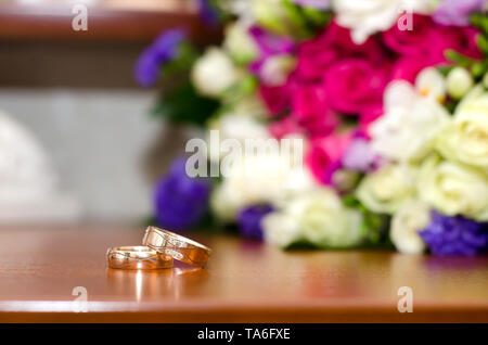 Helles Bild mit Hochzeit Ringe und bunten Hochzeit Blumenstrauß auf dem Tisch Stockfoto