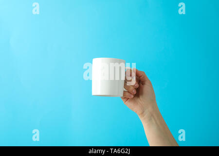 Weibliche Hand, die eine weiße Tasse gegen Farbe Hintergrund, Platz für Text Stockfoto