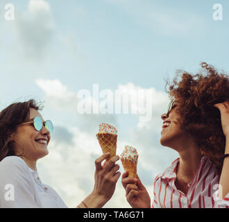 Zwei junge Frauen gemeinsam mit Eistüten. Glückliche junge weibliche Freunde essen Eis im Freien. Stockfoto