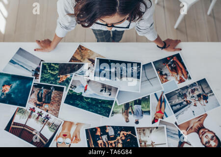 Blick von oben auf eine Fotografin arbeiten im Studio mit Blick auf die Ausdrucke liegen auf dem Schreibtisch. Fotografin der Wahl das beste Bild aus mehreren phot Stockfoto