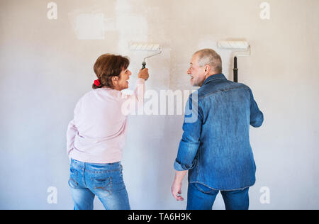 Ansicht der Rückseite des Senior paar Malerei Mauern im neuen Haus, Umzug Konzept. Stockfoto