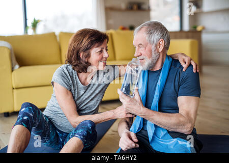 Ein älteres Paar in Innenräumen zu Hause, macht Übung auf dem Boden. Stockfoto