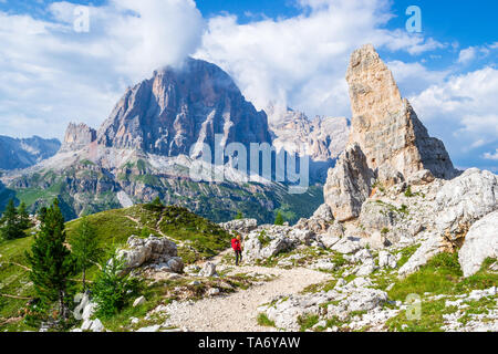 Mädchen mit roten Rucksack auf die Cinque Torri Tour, mit Blick in Richtung Castelletto, Tofana di Rozes, Tofana di Mezzo im Hintergrund. Wanderurlaub in den Stockfoto