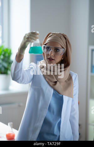 Junge Chemiker stehen und an Flüssigkeit in chemischen Glas Stockfoto