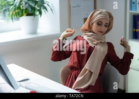 Muslimische Frau nach der Arbeit am Computer zu lange Stockfoto