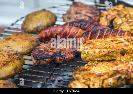 Sortierte lecker Gegrilltes Fleisch mit Kartoffeln über die Kohlen auf einem Grill. Stockfoto