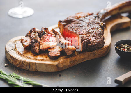 Abgehangenes Rindersteak Marmor Tomahawk auf Holzbrett mit Gewürzen. Close-up, Abendessen Konzept. Stockfoto