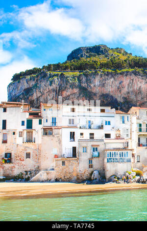 Schönen traditionellen Häusern an der Küste des Tyrrhenischen Meeres in Cefalu, Sizilien, Italien. Hinter den Gebäuden herrlichen Felsen mit Blick auf die Bucht. Die erstaunliche sizilianischen Stadt ist ein beliebter Ort für Touristen. Stockfoto