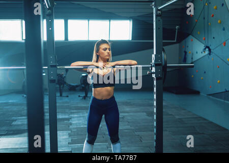 Gymnast Mädchen tun Hocke barbell. Vorderansicht der attraktive junge Frau Stockfoto