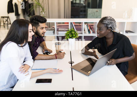 Junge Führungskraft ihre Ideen Präsentation vor Kollegen in einem Meeting. Jungen gemischten rennen Leute diskutieren Arbeit am Schreibtisch im Büro. Stockfoto