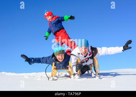 Familie hat Spaß im frischen Schnee an einem sonnigen Wintertag in den österreichischen Alpen Stockfoto