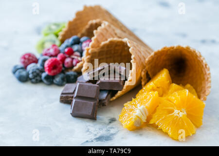 Gesunde Ernährung Konzept - Früchte und Gefrorene Beeren in Eistüten auf rustikalen Hintergrund Stockfoto