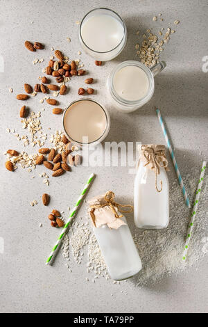 Vielzahl von Nicht-Milchprodukte vegan laktosefrei Nüssen und Getreide, Milch, Mandeln, Haselnuss, Kokos, Reis, Hafer in Glasflaschen mit Strohhalm und Zutaten oben ov Stockfoto