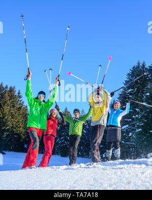 Eine Gruppe von gut gelaunten Menschen, die sich einem Schneeschuh Wanderung in der winterlichen Natur an einem kalten, sonnigen Tag Stockfoto