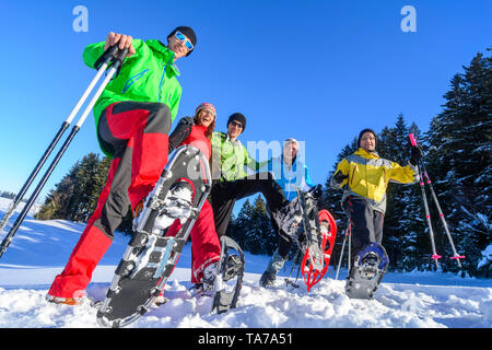 Eine Gruppe von gut gelaunten Menschen, die sich einem Schneeschuh Wanderung in der winterlichen Natur an einem kalten, sonnigen Tag Stockfoto