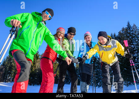 Eine Gruppe von gut gelaunten Menschen, die sich einem Schneeschuh Wanderung in der winterlichen Natur an einem kalten, sonnigen Tag Stockfoto