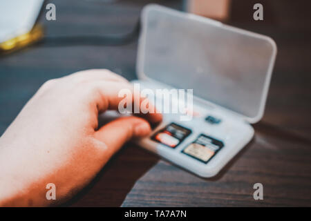 Von Hand gepflückt SD-Karte in einer Aufbewahrungsbox aus Kunststoff auf dem hölzernen Tisch in tragbaren elektronischen Geräten wie Kamera oder Camcorder zu setzen. Stockfoto