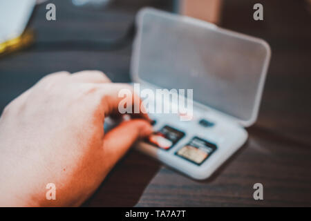 Von Hand gepflückt SD-Karte in einer Aufbewahrungsbox aus Kunststoff auf dem hölzernen Tisch in tragbaren elektronischen Geräten wie Kamera oder Camcorder zu setzen. Stockfoto