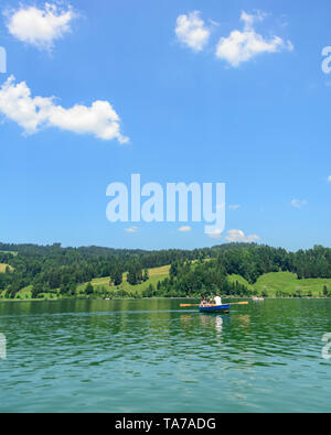 Familie tour mit Ruderboot auf einem See namens Großer Alpsee im Allgäu Berge Stockfoto