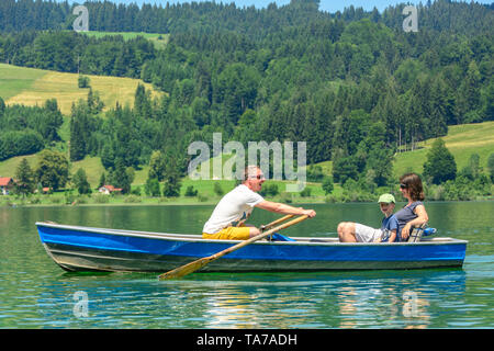 Familie tour mit Ruderboot auf einem See namens Großer Alpsee im Allgäu Berge Stockfoto