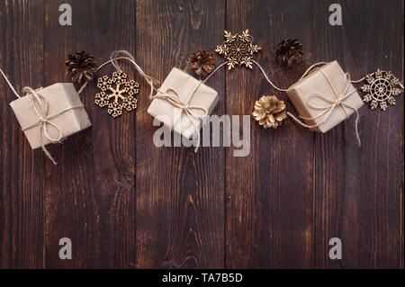 Weihnachtskarte. Kraft Geschenkboxen mit Seil und Schneeflocken, Stöße auf einem Holzhintergrund mit Platz für Ihren Text Stockfoto