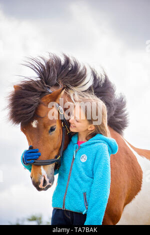 Islandpferd. Mädchen schmusen mit Pinto horse. Österreich Stockfoto