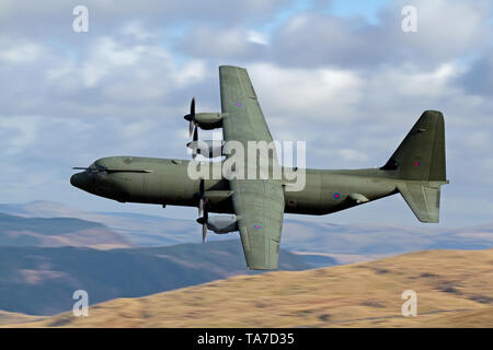 RAF Lockheed C-130 Hercules flying low level in der Mach Loop in Wales, Großbritannien Stockfoto