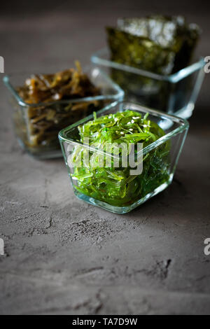 Traditionelle japanische Chuka Wakame Algen Salat und knusprig geröstet Nori Blätter in Glasschale auf dunklem Hintergrund mit Kopie Raum Stockfoto