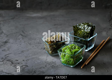 Traditionelle japanische Chuka Wakame Algen Salat und knusprig geröstet Nori Blätter in Glasschale auf dunklem Hintergrund Draufsicht mit Kopie Raum Stockfoto