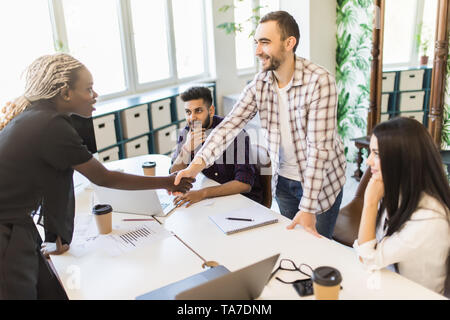 Zwei Mitarbeiter die Hände schütteln bei Treffen der Team im Büro Stockfoto