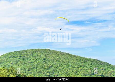 Gleitschirm fliegen über Grünen Berge auf Koh Larn oder Coral Island Stockfoto