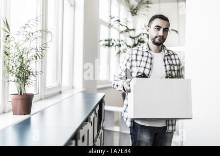 Traurig Geschäftsmann seine Firma verlassen, während er eine Box in der Hand Stockfoto