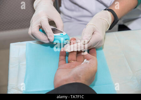 Arzt die Blutprobe von Boy's Finger. Diabetes Konzept. Zucker im Blut. Healthcare Konzept. Junge Mann in Uniform. Weißes Fell. Medizinische Stockfoto