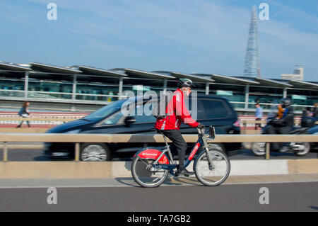 Ein Mann reiten Santander Gemeinschafts-Fahrrad (Motion Blur) auf die Blackfriars Bridge mit Bahnhof Blackfriars und Teil der Shard in Aussicht Stockfoto