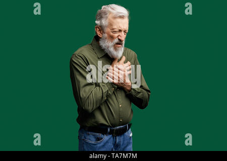 Unglücklich kranken Mann in Grün shirt leiden unter Schmerzen im Herzen. Herzinfarkt oder schwere Verdauungsstörungen. Nahaufnahme, Seite, Ansicht Foto. alte Mann hat Verstauchungen sein a Stockfoto