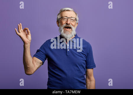 Happy positive stattlichen alten Mann zeigt Ok Zeichen, keine Probleme, Gesundheit ist ok. Ist alles ok. bis Portrait schließen. Isolierte blauen Hintergrund. Glück, suc Stockfoto