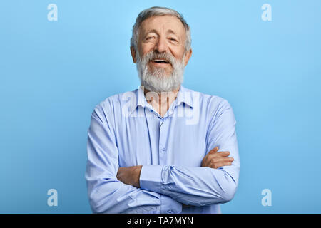 Freundlich aussehenden Mann mit verschränkten Armen, Lachen auf etwas, in die Kamera schaut. bis Foto schliessen. Glück, Gefühl und Emotion Stockfoto