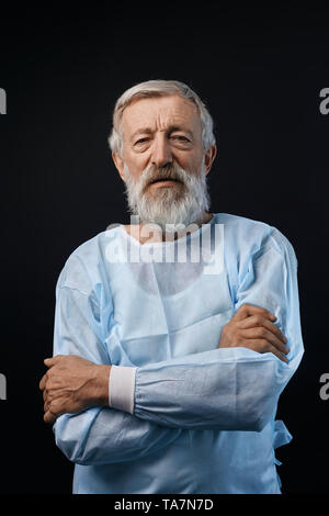 Fröhliches happy Reife stehenden Patienten mit verschränkten Armen, und wenn man die Kamera im Krankenhaus. Isolierte schwarze Hintergrund. Medizin, Freizeit, Wellness Stockfoto