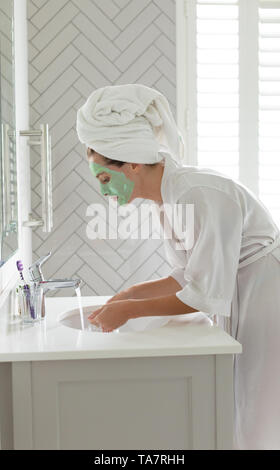 Frau waschen Ihr Gesicht Maske im Waschbecken im Bad zu Hause Stockfoto