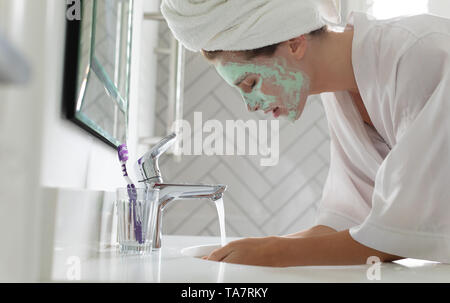 Frau waschen Ihr Gesicht Maske im Waschbecken im Bad zu Hause Stockfoto