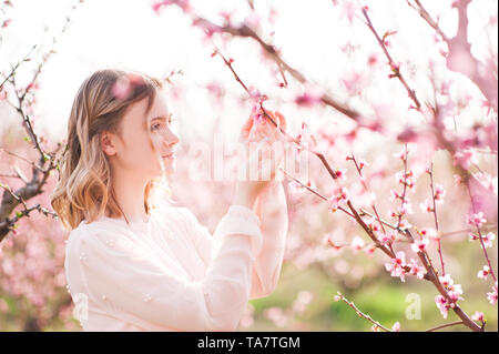 Schöne blonde teen Mädchen 15-16 Jahre alt in Peach Orchard Nahaufnahme posieren. Frühling Saison. Stockfoto