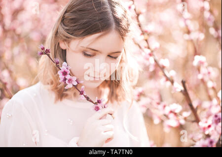 Lächelnde blonde Mädchen, dass Peach Blumen im Freien Nahaufnahme. Frühling Saison. Stockfoto