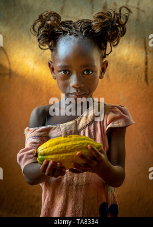 Cute afrikanische Mädchen mit einem Kakao Obst pod in ihren Händen, Région de l'Esperance, Yamoussoukro, Elfenbeinküste Stockfoto