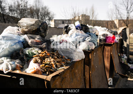 Mülltonnen sind mit Pakete mit Abfall überfüllt Stockfoto